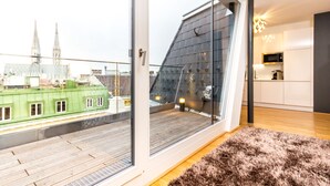 Een modern appartement met een groot raam, uitzicht op een stadsgezicht en een keukenhoek.