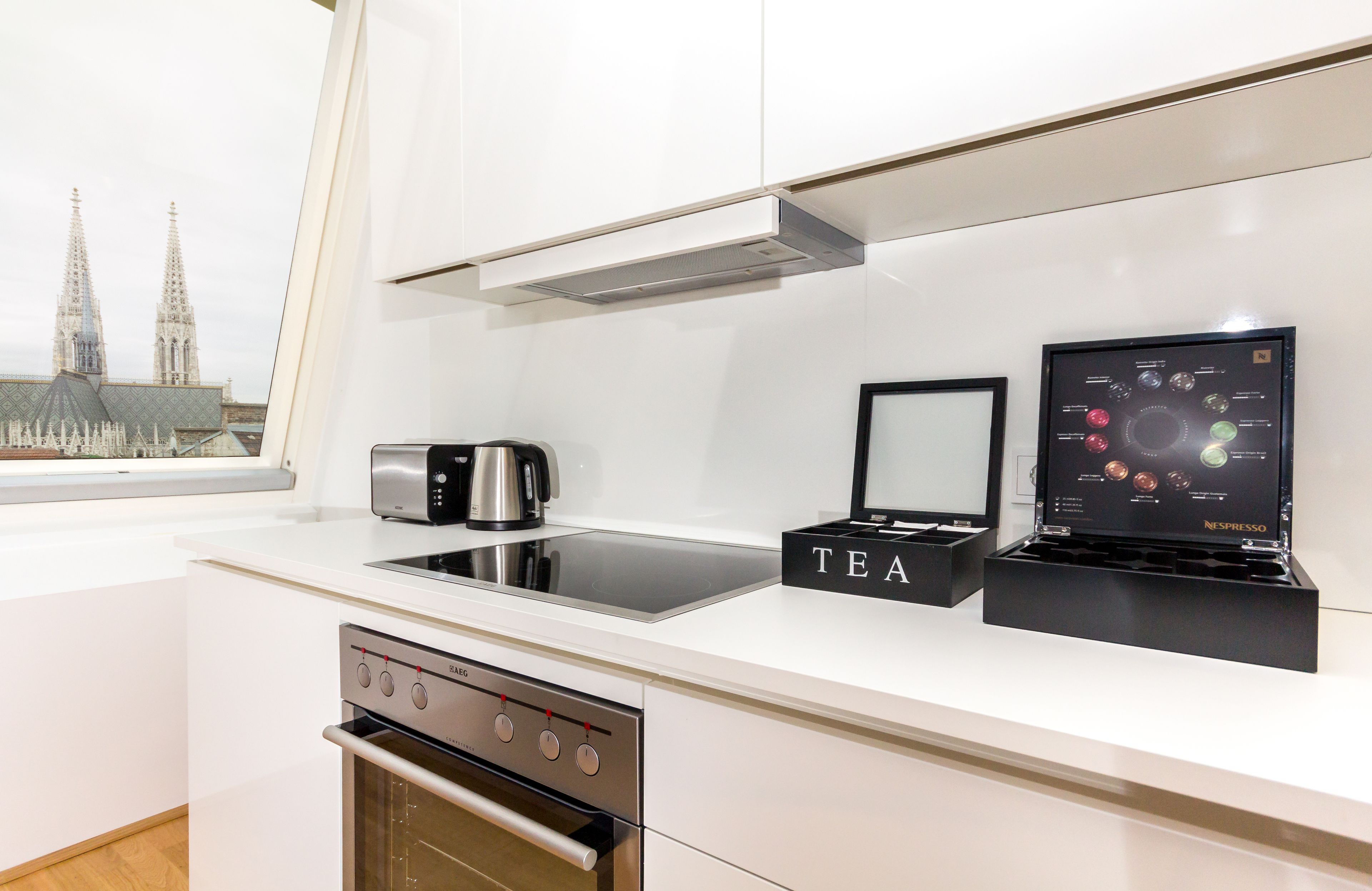Une cuisine moderne équipée d’une machine à expresso intégrée, d’une boîte à thé et d’un présentoir Nespresso.