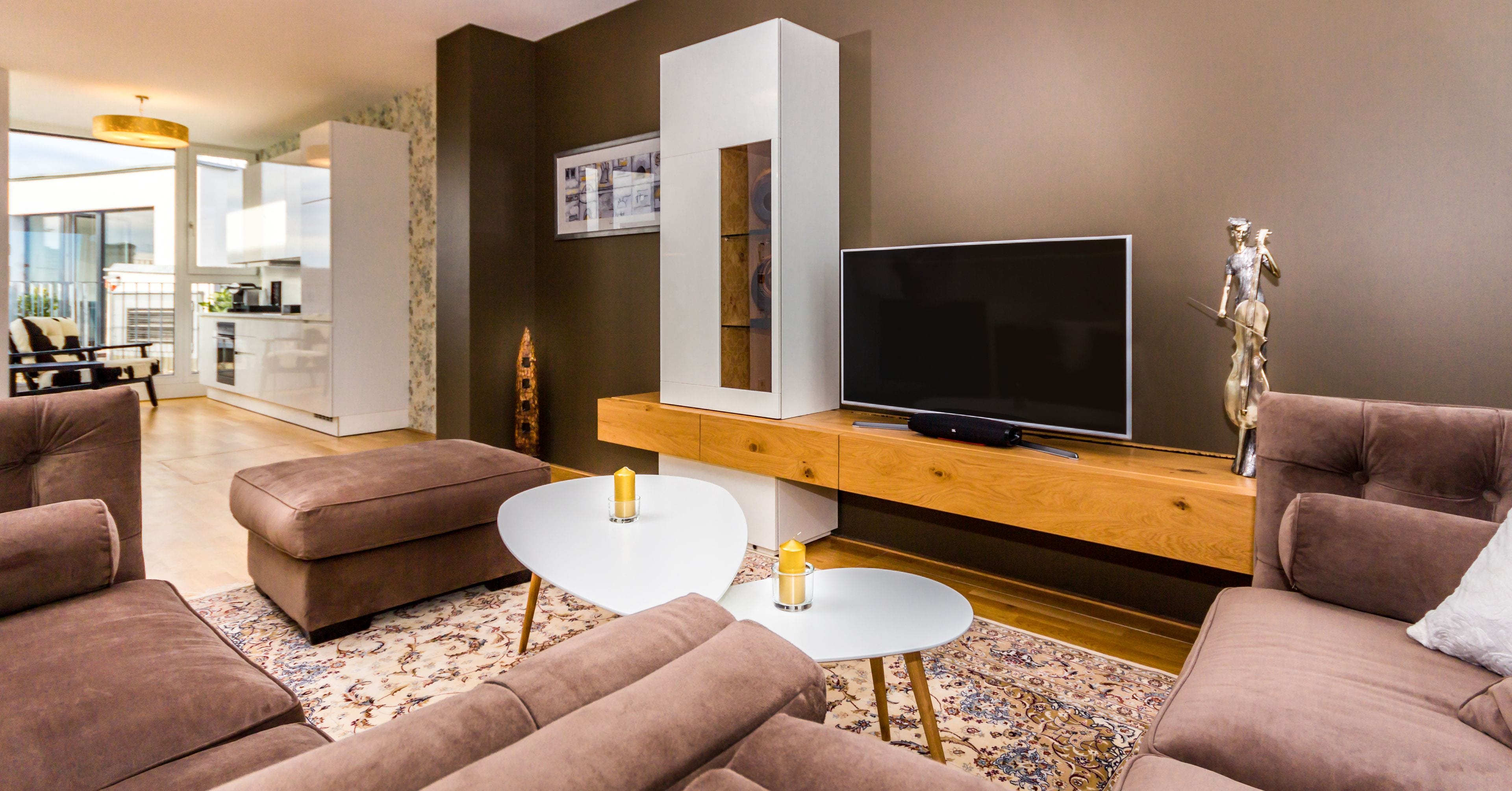Ein modernes Wohnzimmer mit Flachbildfernseher, braunen Sofas, einem weißen Couchtisch und einer Holzkonsole.