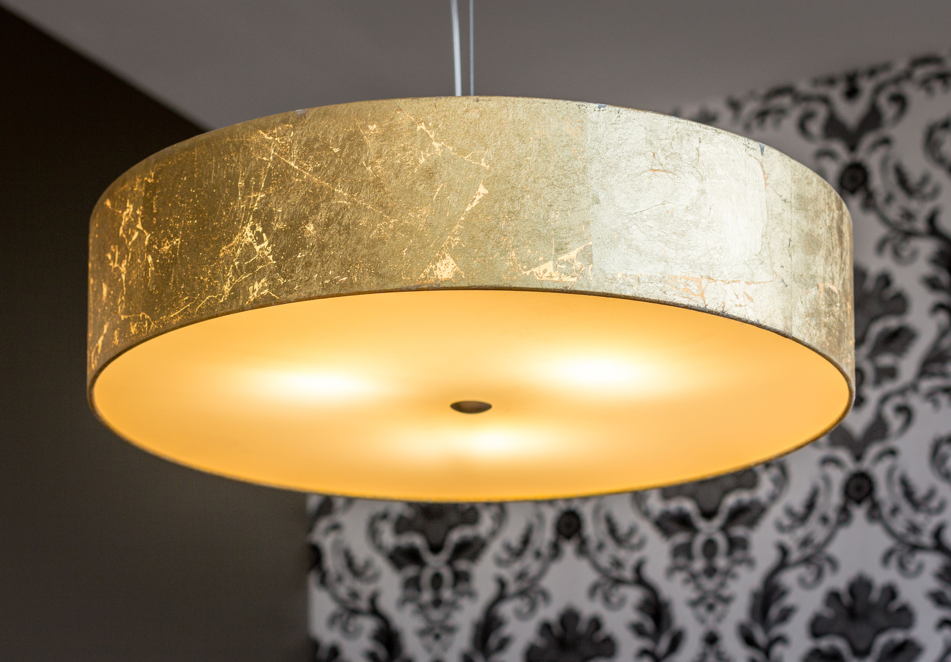 Un luminaire suspendu doté d’un abat-jour texturé de couleur or.