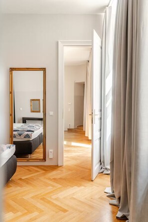 Une chambre à coucher avec un lit, un miroir et une porte donnant sur une autre pièce.