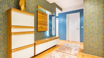 Una habitación con un armario de madera, un espejo y papel tapiz estampado.