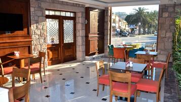 Un comedor interior con paredes de piedra, muebles de madera y vistas a la calle.