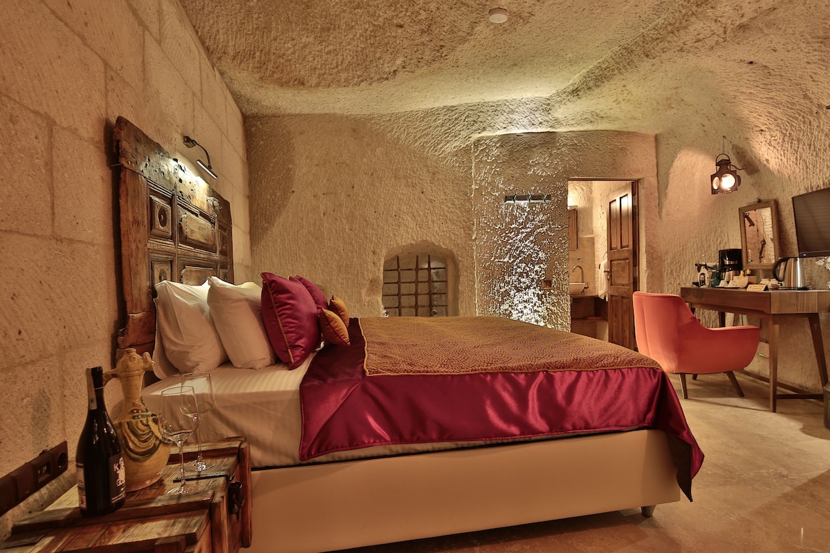 A bedroom with a bed, a desk, a chair, a wine bottle, and a glass.
