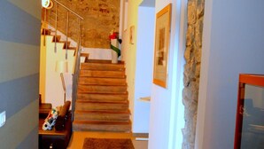 Um corredor com escadas, uma parede de pedra e um quadro emoldurado.