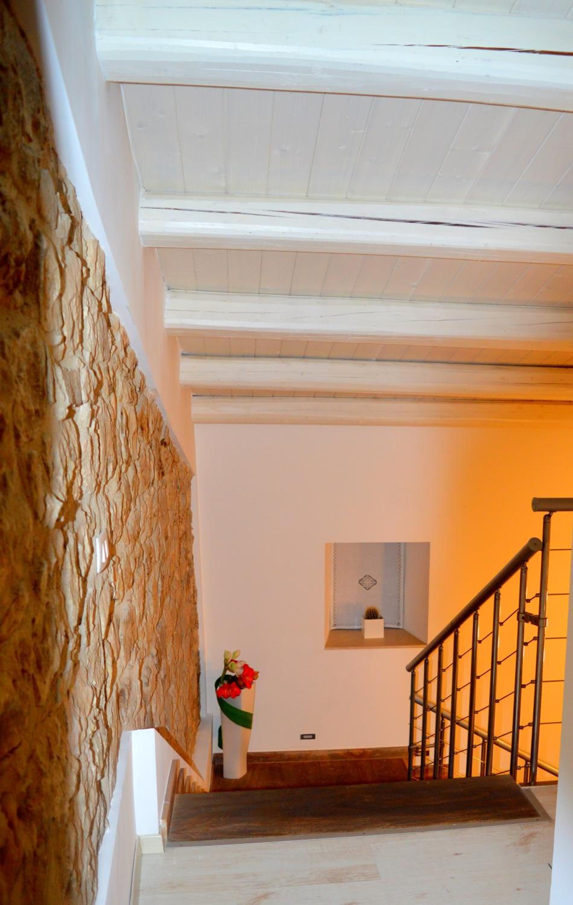 Una escala amb barana de fusta i paret blanca, amb un objecte decoratiu petit al descans.