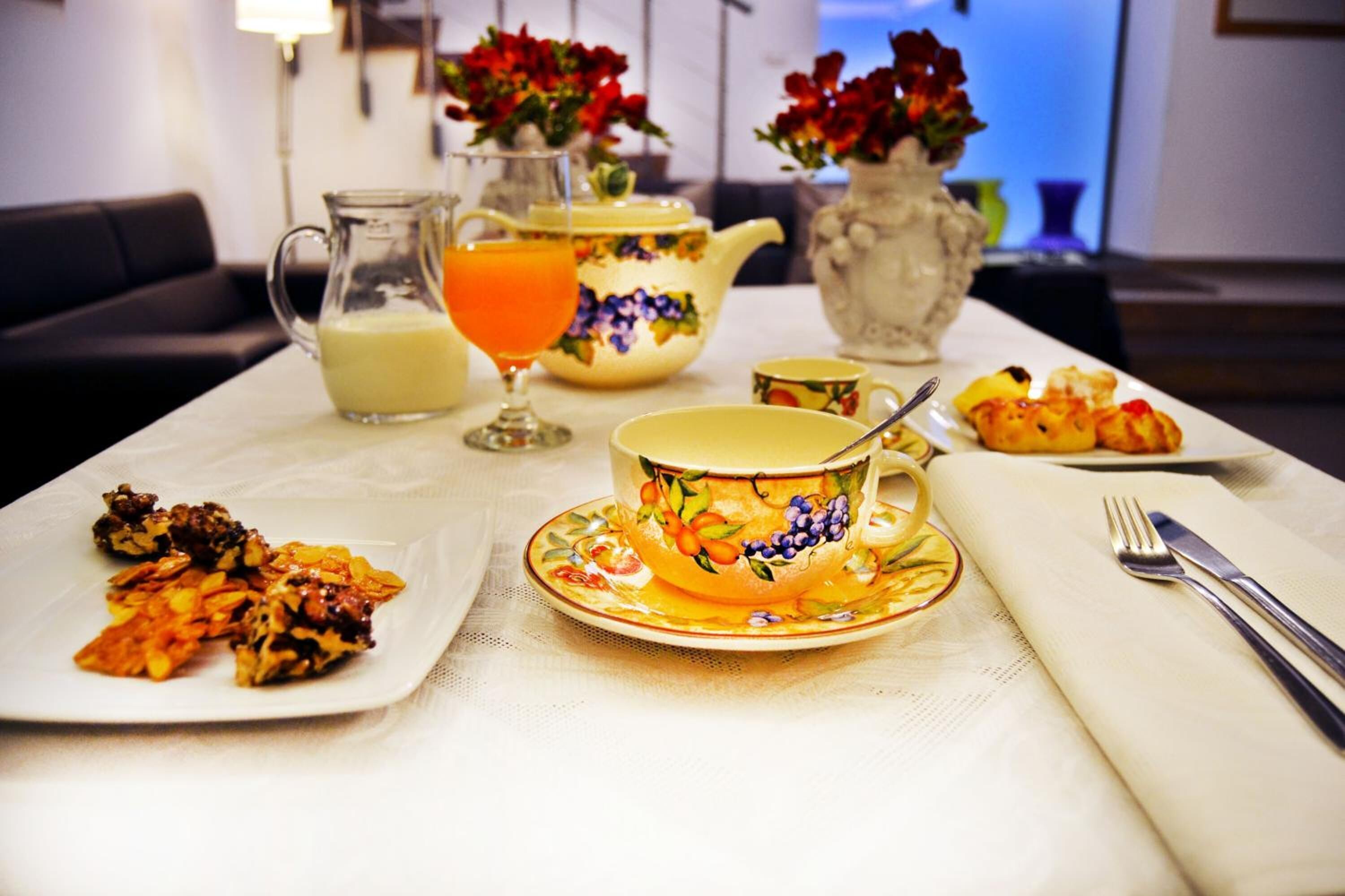 A breakfast setting with a teapot, jug, and fruit on a table.