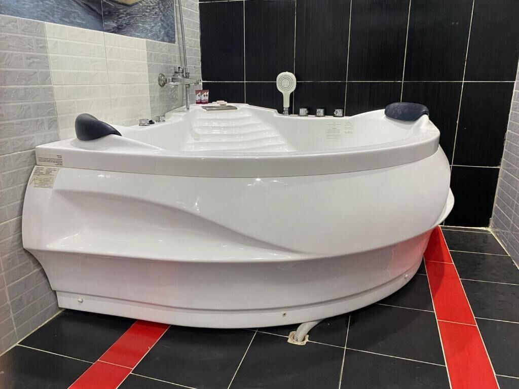 A white hot tub in a bathroom with black and red tiled flooring.