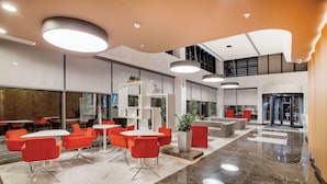 Un hall d’entrée spacieux, doté de mobilier moderne, agrémenté d’une plante d’ornement et d’un escalier menant à un niveau supérieur.