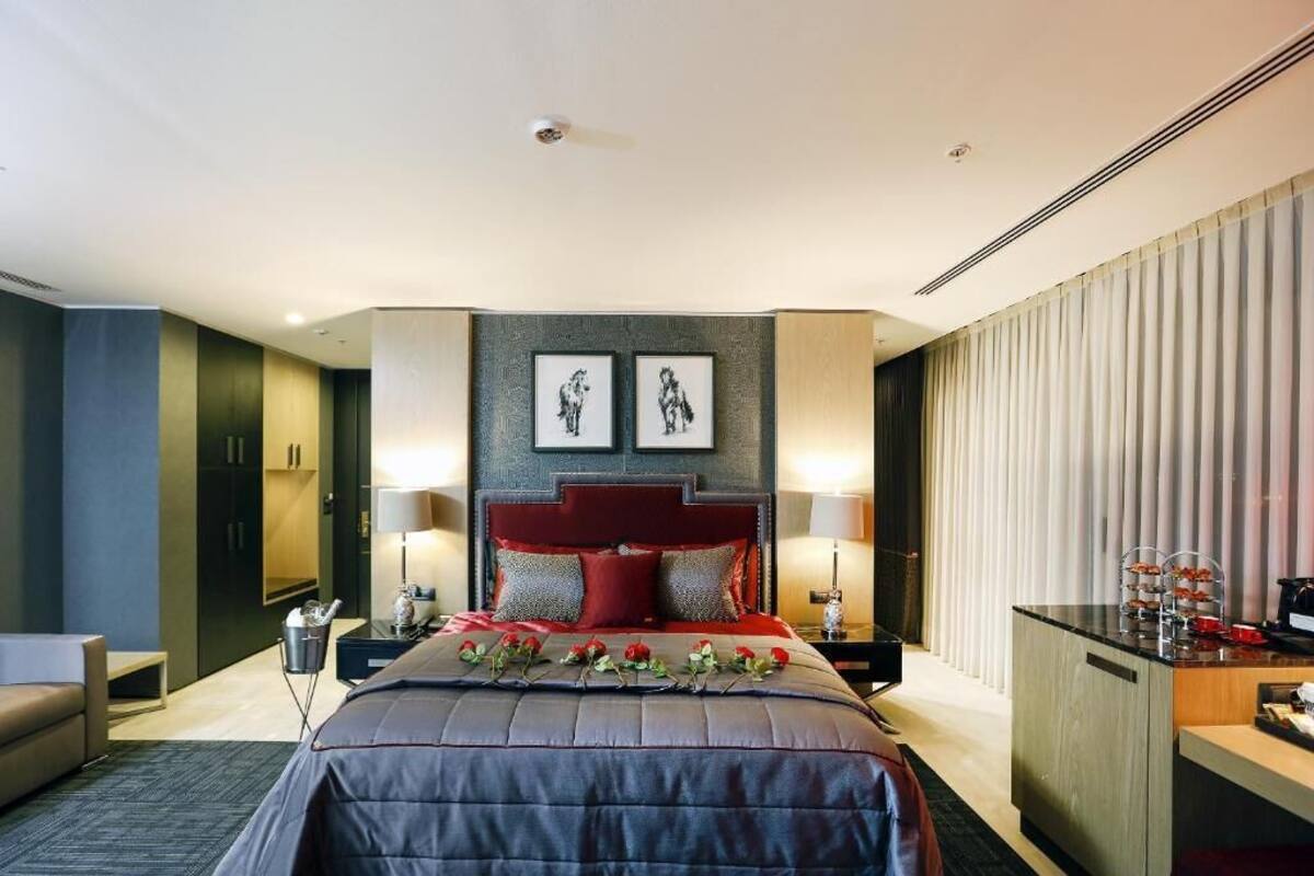 A modern hotel room with a large bed, a desk, and a seating area.
