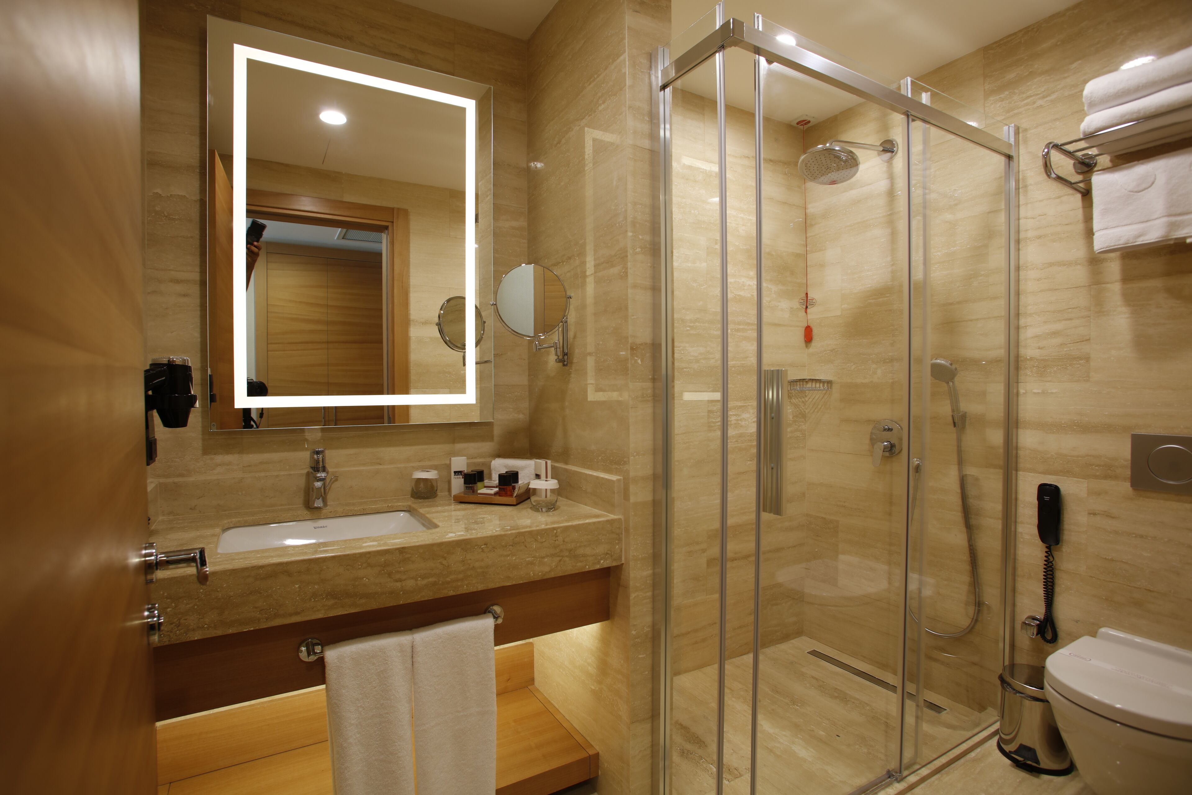 Un baño moderno con ducha de vidrio, lavamanos con espejo e inodoro.