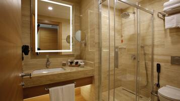 Un baño moderno con ducha de vidrio, lavamanos con espejo e inodoro.