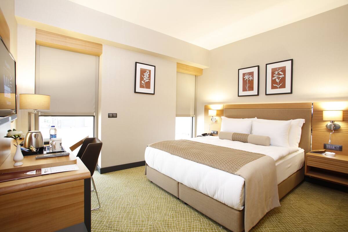A hotel room with a large bed, bedside tables, a desk, and a chair.