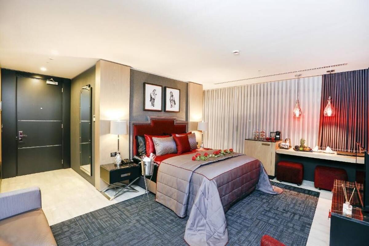 A modern hotel room with a large bed, bedside tables, a desk, and a seating area.