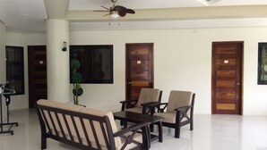 A spacious room with a sofa, chairs, a table, and a ceiling fan. - Inngo Tourist Inn (El Nido)