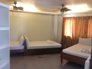 Een hotelkamer met twee eenpersoonsbedden, een plafondventilator en een raam met gordijnen.
