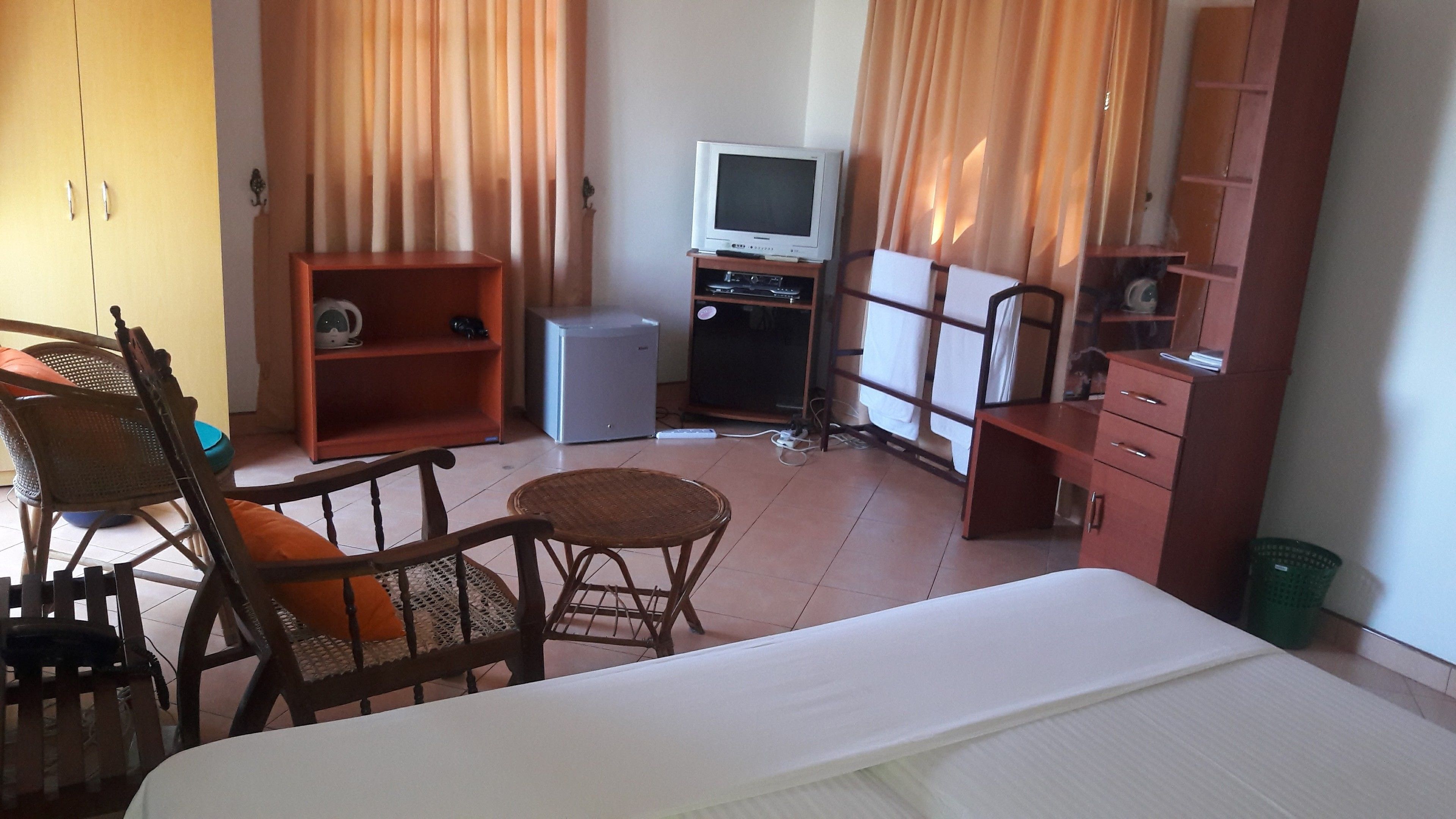 A hotel room with a bed, a desk with a computer, a chair, a television, and a wardrobe.
