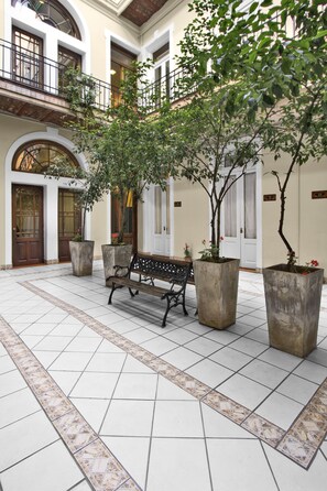 Un patio con un banco, plantas en macetas y suelo de baldosas.