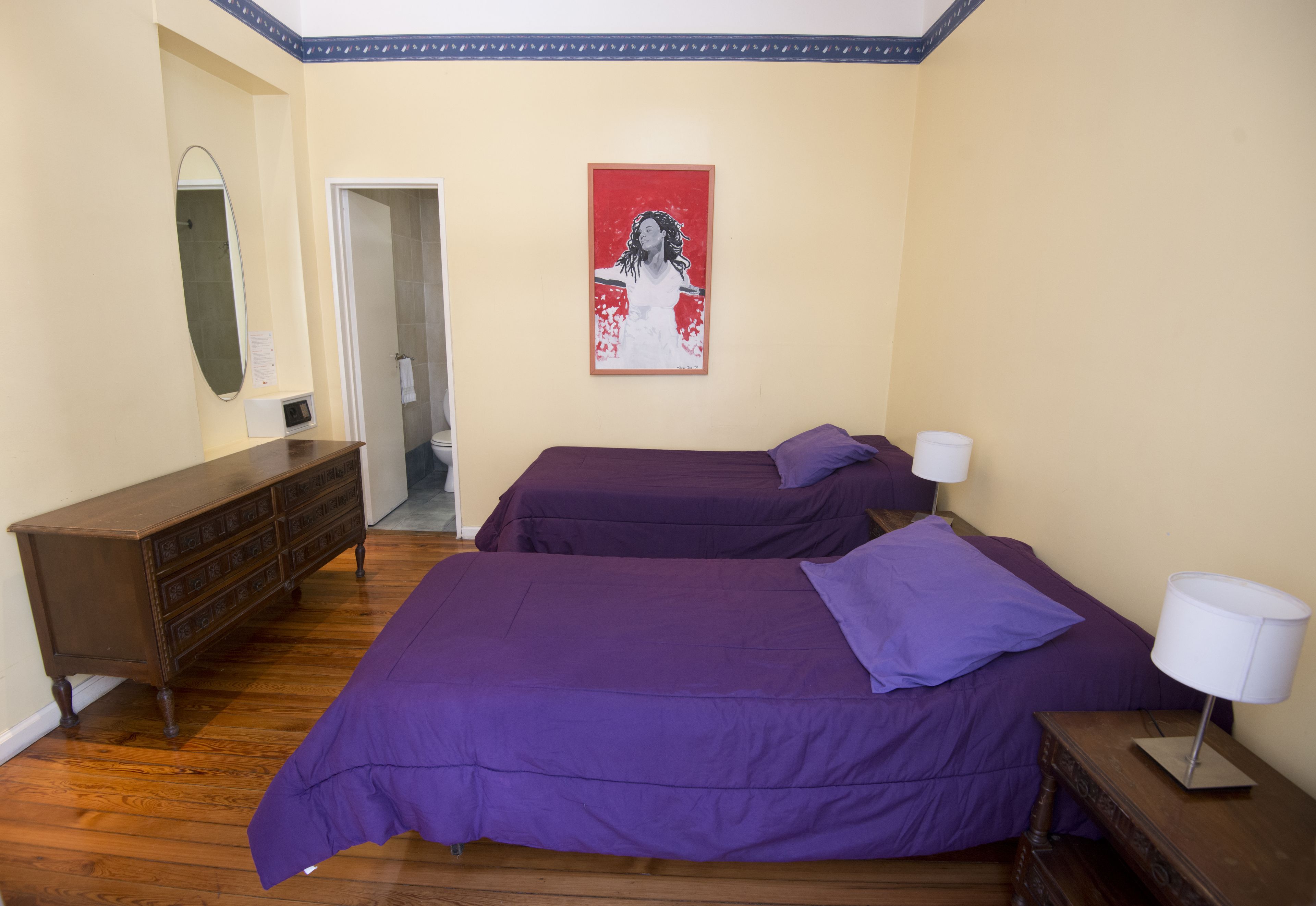 A bedroom with two beds, a dresser, a mirror, and a framed picture on the wall.