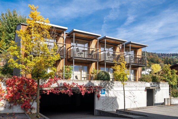 A modern building with a covered outdoor area, a parking sign, and a view of a natural landscape. - Hotel Restaurant Schönbühl (Hilterfingen)