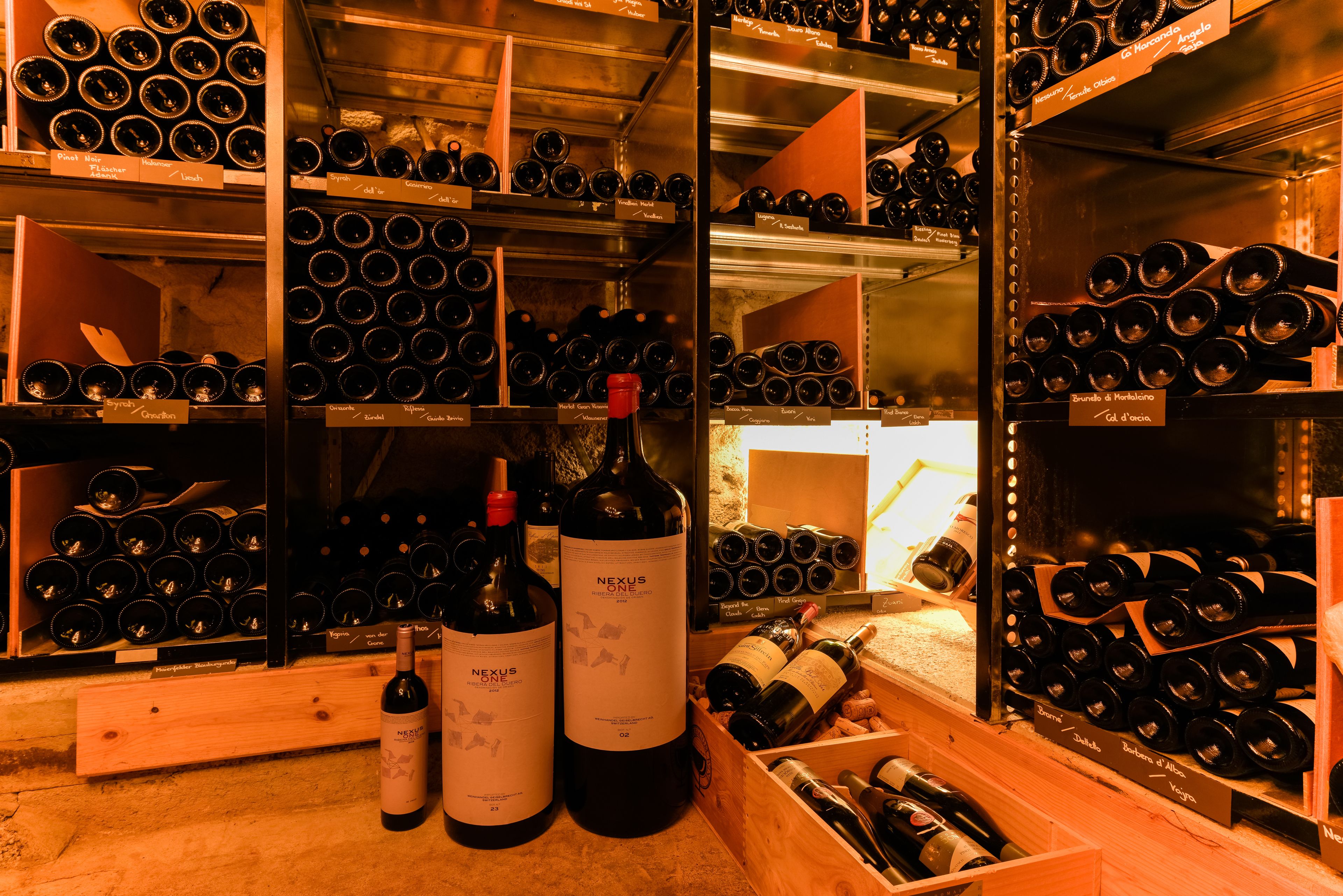 A wine cellar with multiple shelves and wooden crates filled with wine bottles.