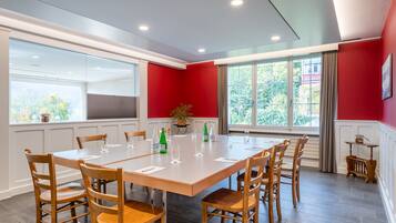 Un salón de conferencias con una gran mesa, sillas de madera y cristalería.