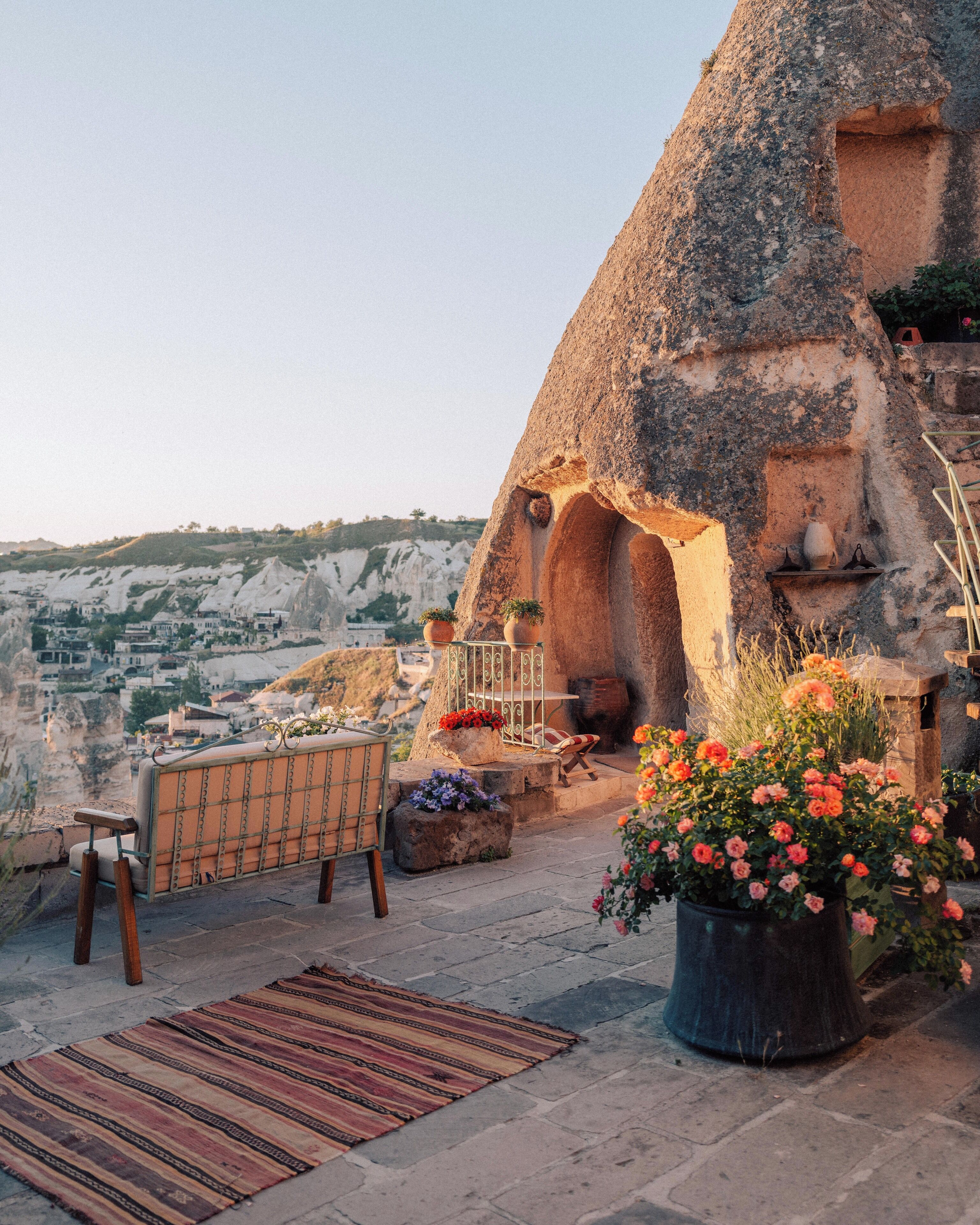 A stone house with a built-in fireplace, outdoor seating, and a view of the surrounding landscape.
