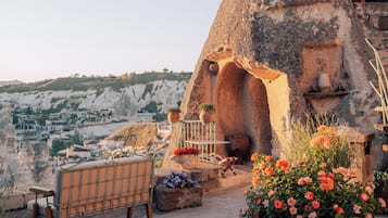 A stone house with a built-in fireplace, outdoor seating, and a view of the surrounding landscape.