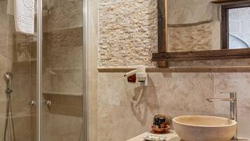 A bathroom with a glass-enclosed shower, a stone sink, and a wooden vanity.