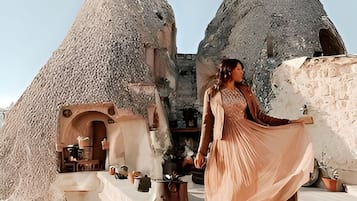 A woman in a dress standing in front of traditional stone houses with conical roofs.