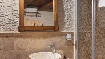 A bathroom with a stone sink, wooden countertop, and a mirror above it.