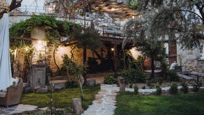 A stone pathway leading to a rustic building with a stone facade and a balcony overlooking a garden.