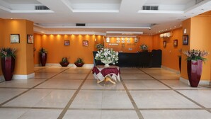 A hotel reception area with a reception desk, potted plants, and a clock on the wall. - Terrace Furnished Apartments Fintas 2 (Fintas)