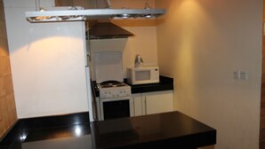 A kitchen with a black countertop, white cabinets, a microwave, and a stove. - Terrace Furnished Apartments Fintas 2 (Fintas)