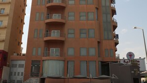 A multi-story building with balconies, a parking area, and a street lamp. - Terrace Furnished Apartments Fintas 2 (Fintas)