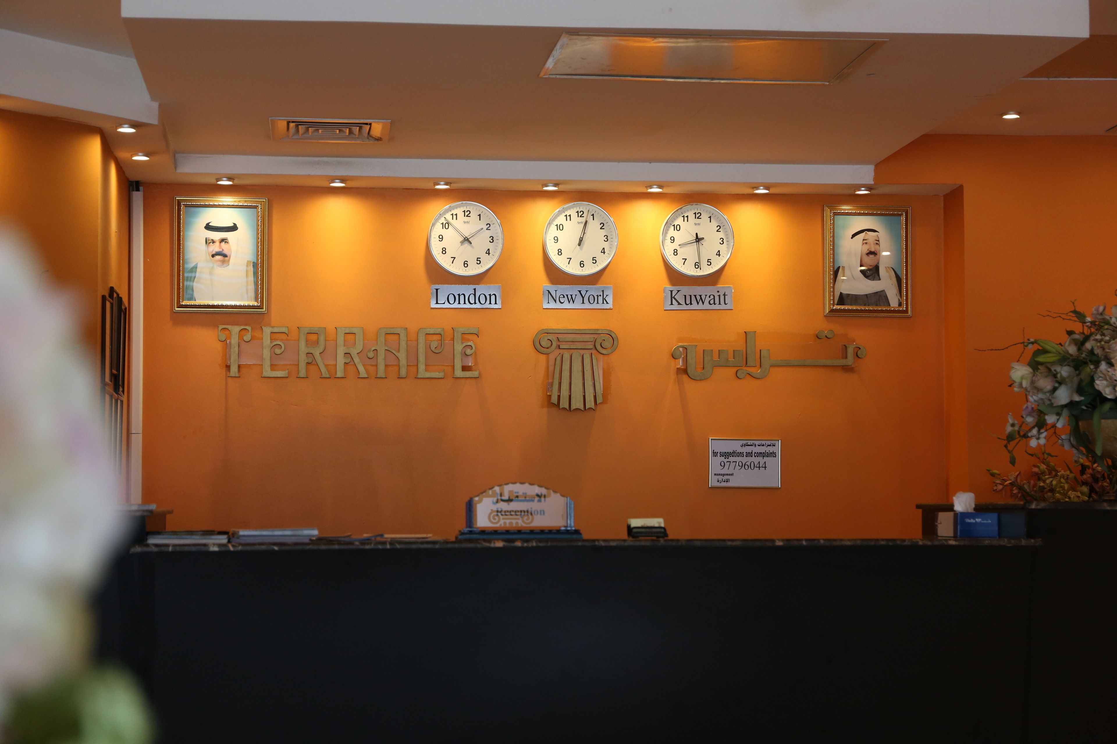 A reception desk with clocks displaying times for London, New York, and Kuwait.