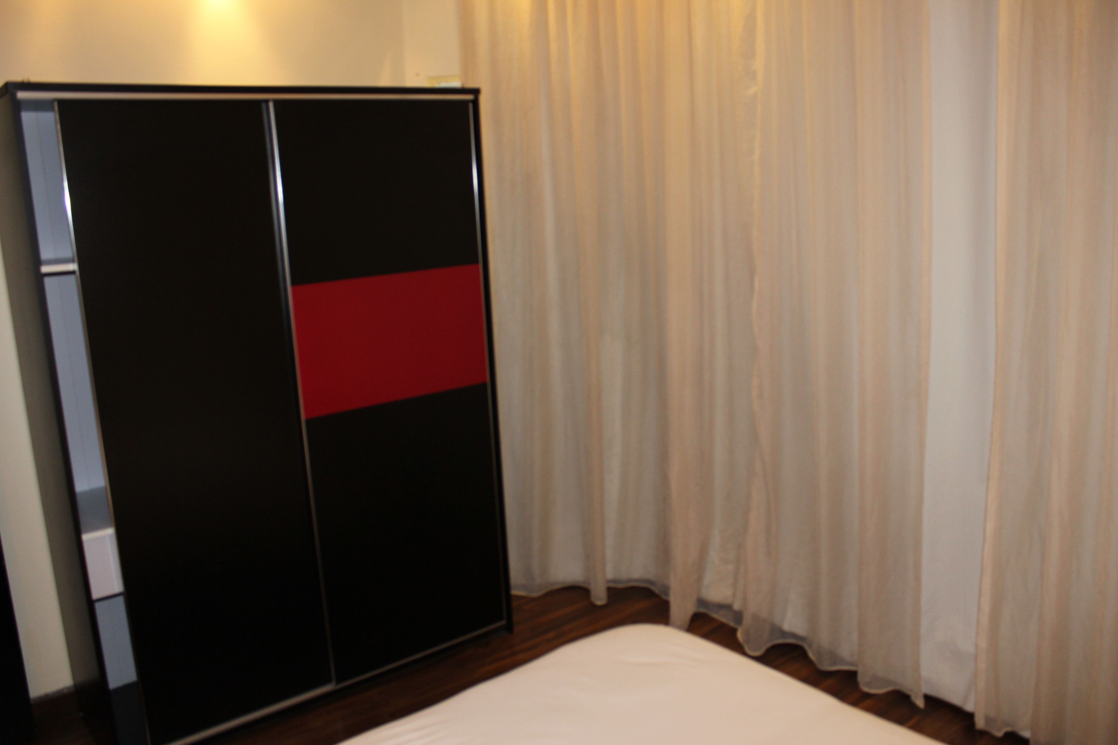 Una habitación con cama, armario y cortina.