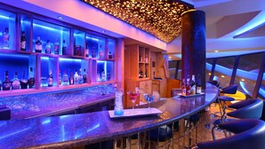 A bar area with shelves of bottles, a bar counter, and bar stools. - RS Sarovar Portico Palampur (Palampur)
