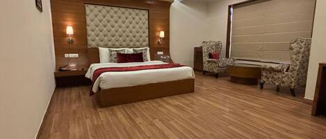 A bedroom with a large bed, two bedside lamps, a desk, and a chair.