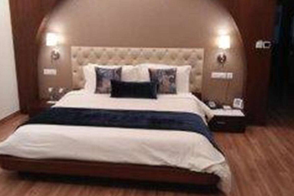 Ein Schlafzimmer mit einem großen Bett, einem gepolsterten Kopfteil und zwei Nachttischlampen.