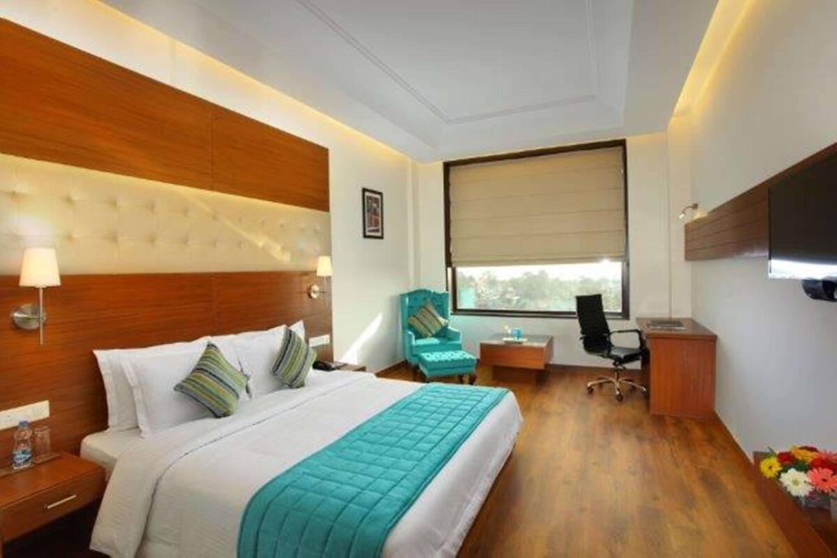 Ein Hotelzimmer mit einem großen Bett, einem Schreibtisch, einem Stuhl und einem Fernseher.