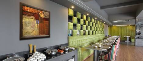 A buffet setup with a variety of food items, a long table, and a seating area with cushioned chairs.