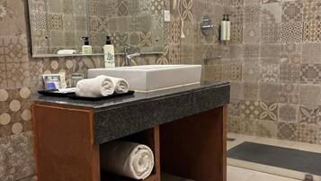 A bathroom with a large mirror, a sink, a shower, and patterned tiles.