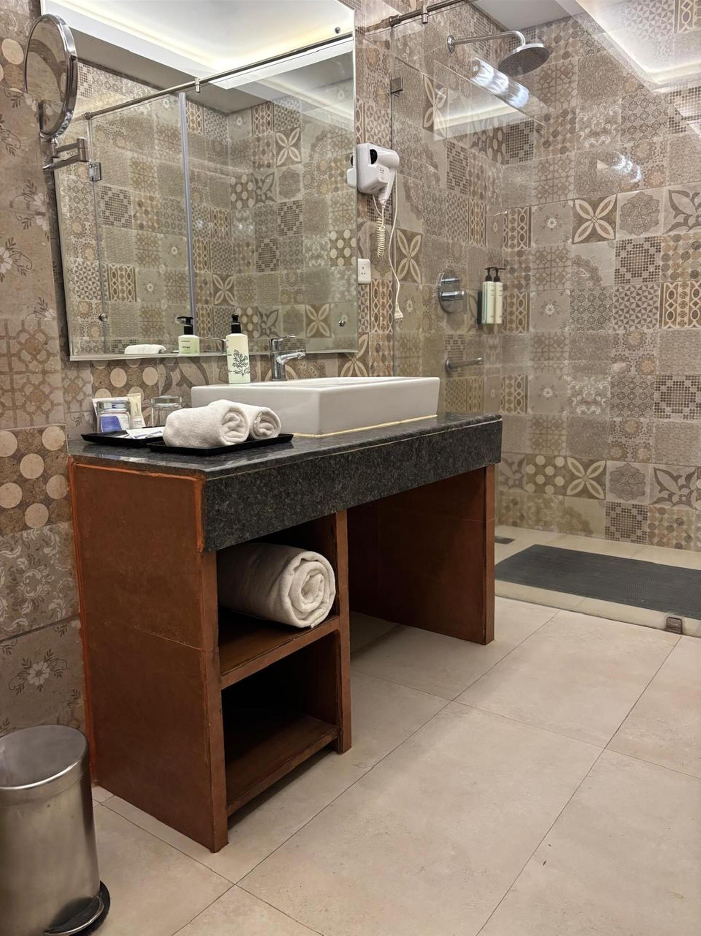 Un baño con un espejo grande, un lavamanos y una zona de ducha.