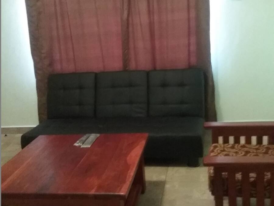 A living room with a black sofa, a wooden coffee table, and a patterned wooden chair.