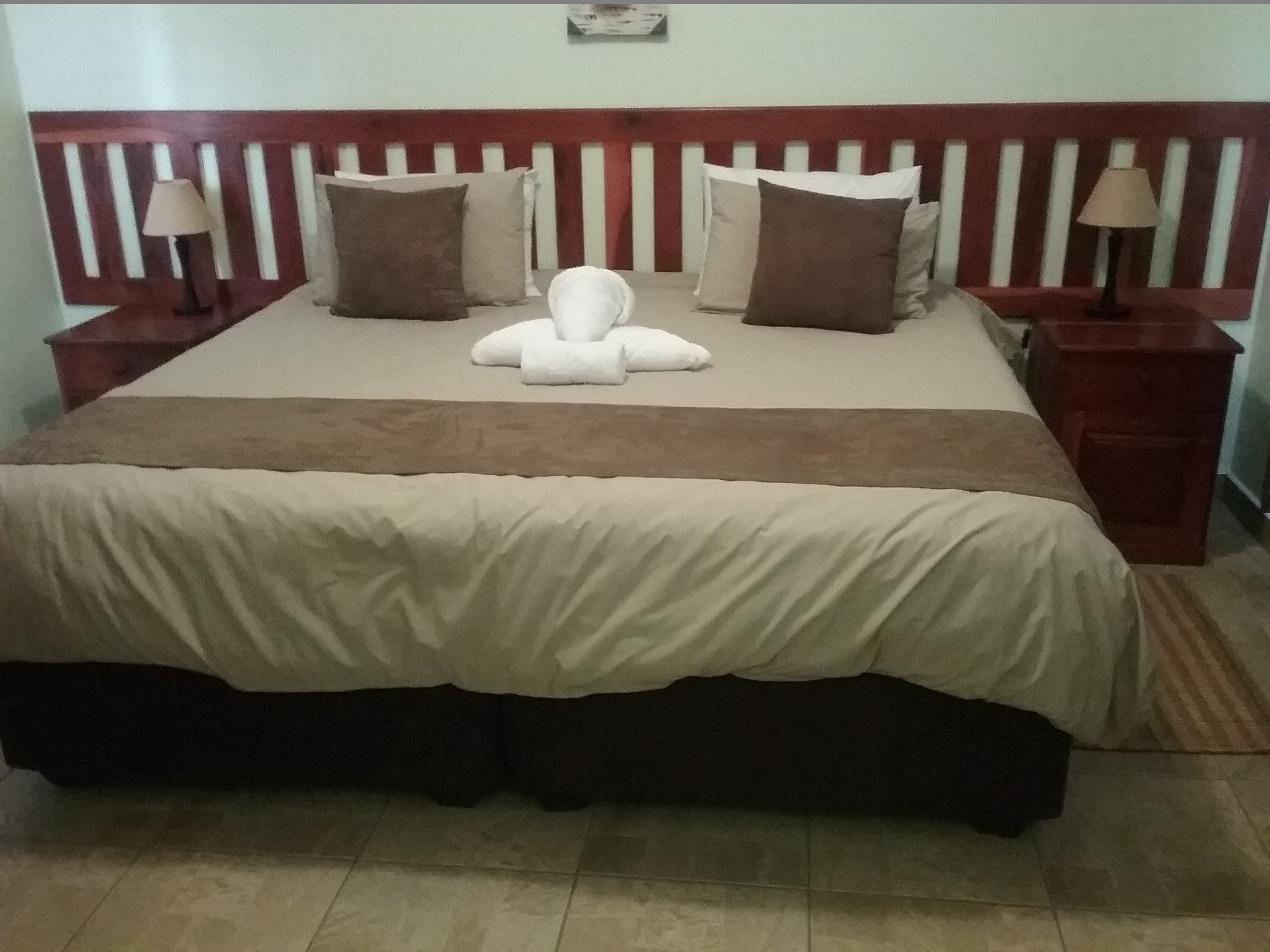 A neatly made bed with a wooden headboard, two bedside tables with lamps, and a brown throw blanket.