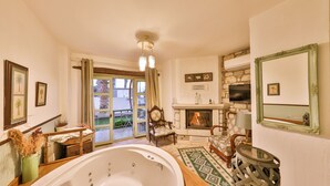 Une pièce spacieuse dotée d’une grande baignoire, d’une cheminée et offrant une vue à travers une porte vitrée.