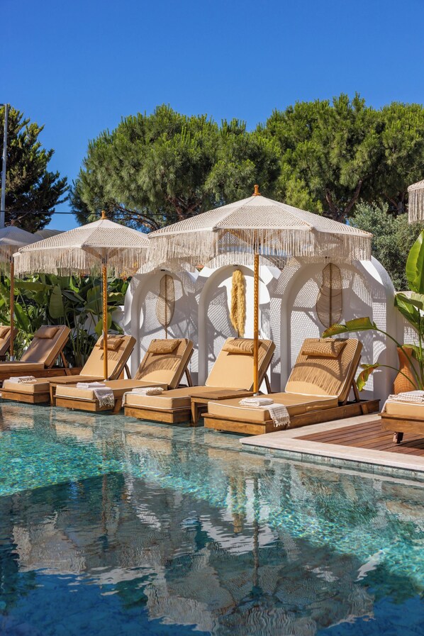 A pool area with lounge chairs and umbrellas.