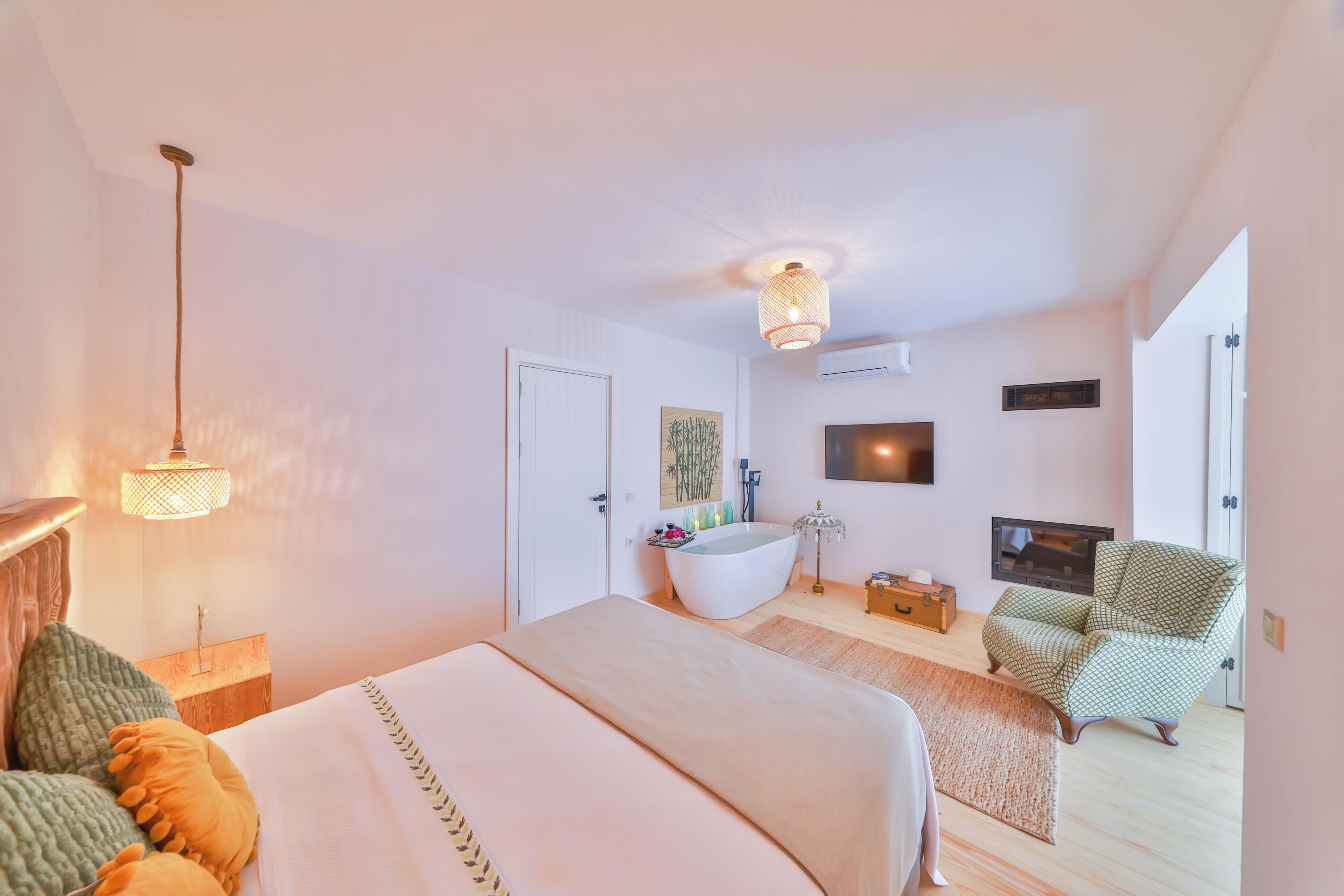 A bedroom with a bed, a bathtub, a TV, and a chair.