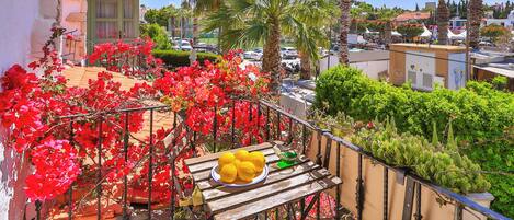 A balcony with a table, chairs, and a plate of lemons.